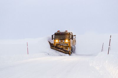 Snøbrøyting i blåtimen. Brøytebil på riksvei 890 Kongsfjordfjellet. Tana kommune. Finnmark.Snow Plough in the blue hour on a mountain road at Finnmark County. Northern Norway.