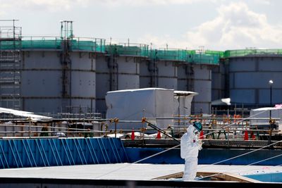 En arbeider står foran tanker fylt med radioaktivt vann ved Fukushima DaiIchi kjernekraftverk. I dag er det ti år siden ulykken.