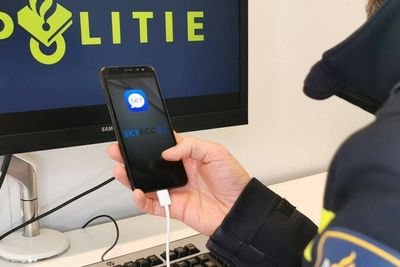 Nederlandsk politimann med en smartmobil som tilsynelatende kjører Sky ECC-appen. Selskapet som står bak tjenesten, hevder derimot at appen på bildet er falsk. Politi fra flere europeiske land har samarbeidet i denne saken.