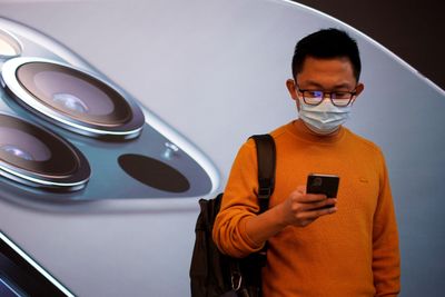 En mann bærer ansiktsmaske mens han venter i en Apple Store i Shanghai, Kina ved lansering av Iphone 12 i fjor høst.