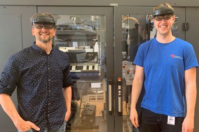 Eivind Adelsten Rosén og Andreas Thoresen med "HoloLens" foran en pakkemaskin.