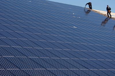 Workers install solar panels on what will be the world's biggest integrated solar panel roof, 36,000 square metres spread over five hangars, at a farm in Weinbourg, eastern France February 12, 2009.   REUTERS/Vincent Kessler  (FRANCE)