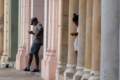 Tilgangen til mobilnettet og internett er delvis gjenopprettet på Cuba etter tre dager med avbrudd i kjølvannet av protester. Bildet viser et par innbyggere i Havana som bruker mobiltelefon med forhåndsbetalt tilgang til wifi-forbindelse.