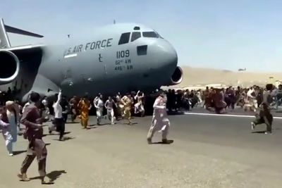 Hundrevis av mennesker springer rundt og klamrer seg fast til et C-17 som takser på flyplassen i Kabul mandag.
