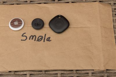 Sporingbrikker fra Apple, Tile og Samsung på toppen av en posekonvolutt som det er skrevet «Smøla» på.