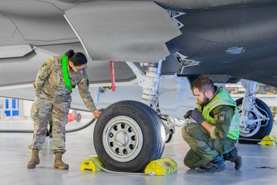 Norsk og amerikansk tekniker jobber på et amerikansk F-35A i et shelter på Ørland flystasjon.