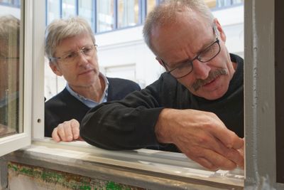 Tor Lømo-Hansen (t.v.) og Gjermund Horten forsøker å se hvor lekkasjene har oppstått som følge av det harde regnet prototyp-vinduet ble utsatt for.