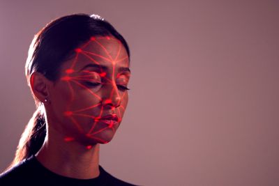 Facial Recognition Technology Concept As Woman Has Red Grid Projected Onto Face In Studio