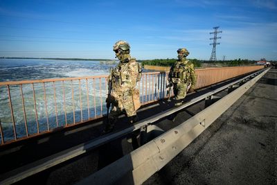 Russiske soldater patruljerer rundt demningen til vannkraftverket i Kakhovka.