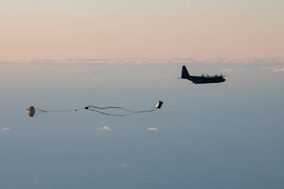 A palletized munitions system falls from the cargo hold of a 352d Special Operations Wing MC-130J Co ...