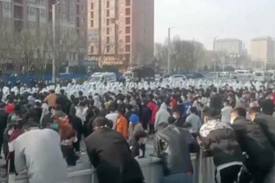 Dette bildet fra onsdag 23. november viser demonstranter som står ansikt til ansikt med sikkerhetspersonell i hvite beskyttelsesdrakter på fabrikkområdet til Foxconns største Iphone-fabrikk i Zhengzhou.