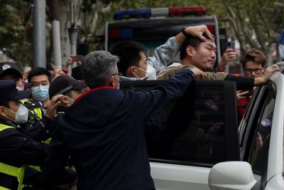 En demonstrant tvinges inn i en politibil i Shanghai. Mange demonstranter spores av politiet.