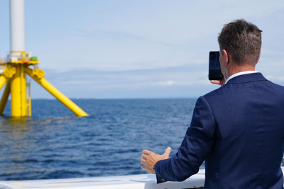 Olje- og energiminister Terje Aasland tar bilde av en havvind-turbin på METCentre utenfor Karmøy.