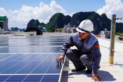 En mann vedlikeholder solcellepanelene på taket til GO-Supermarket i Ha Long City i Vietnam, der Norad har støttet et solcellekraftverk gjennom sin bedriftstøtteordning.