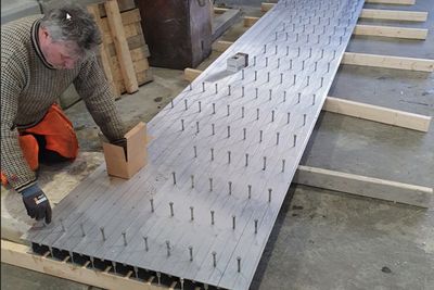 I samvirkekonstruksjonen ligger aluminiumprofilene i bunn, og får et lag betong støpt på oversiden. Boltene er av stål. Siden aluminium ikke korroderer er det ikke behov for overdekning og konstrusjonen blir smekrer, tynnere og lettere.