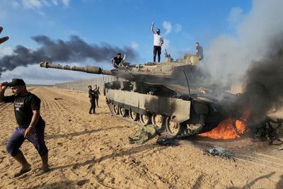 Palestinere feiret på en ødelagt israelsk stridsvogn på Gazastripen lørdag.
