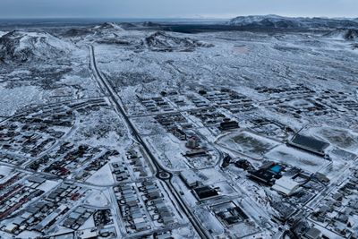 Lavaområdet som har oppstått i forbindelse med den seneste vulkanske aktiviteten kan skimtes i bakgrunnen av Grindavik på halvøya Reykjanes. Bildet er tatt 21. desember i fjor.