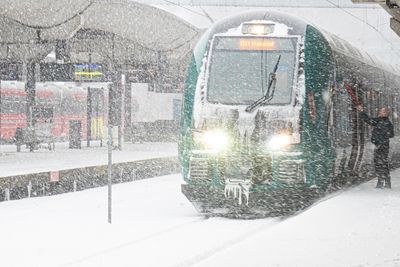 En togfører skraper is av toget før avgang fra Oslo S i formiddag. En stund ble alle togene stoppet.