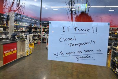 Et skilt varsler kunder om en midlertidig stenging på grunn av IT-problemer i en Liquorland-butikk i Canberra, Australia.