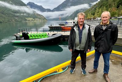 Frank Bonsaksen (t.v.) driver sightseeing i Geirangerfjorden. Her med den gjennomprøvde elbåten i bakgrunnen. Her sammen med Trond Strømgren fra motorleverandør Evoy.