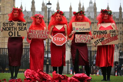 November 8, 2024, London, England, UK: Protesters stand holding signs supporting their views in Parliament Square wearing red dresses and veils. Protesters from Fossil Free London host a die-in outside the Houses of Parliament to call on the government to stop the Rosebank oil field in the North Sea. The decision to approve the oilfield is being challenged in the court