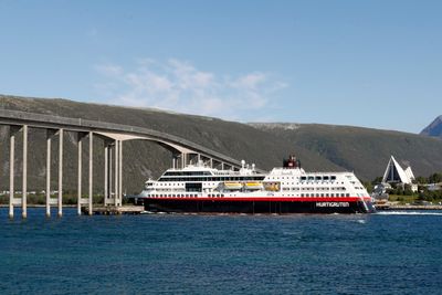 Hurtigruten Trollfjord under Tromsøbrua i sommer. Nå får selskapet nye eiere.