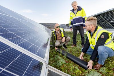 Anders Besvold Hansen viser Trond Spande og Magnar Aske hvor det kan være lurt å plassere sensoren: Der snøen lander når den glir ned fra solcellene.