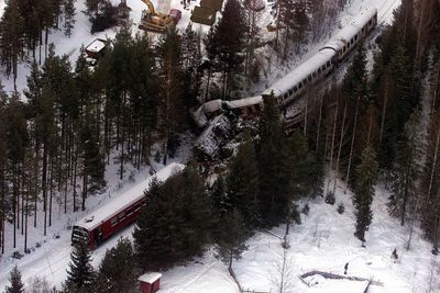 RENA 20000105: Togulykke på Rørosbanen, 19 mennesker omkom. Hjelpemannskaper undersøker de utbrente vrakrestene etter togulykken. Oversikt fra luften over ulykkesstedet.