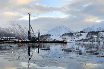 Pelegruppe i havet utenfor sjøfyllinga ved Leirbakken. Inne på fyllingen synes bruas laveste betongsøyle. Bak til venstre ligger peler klare til å fløtes ut til riggen.