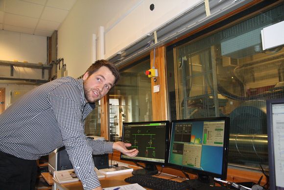 Forskningsingeniør Mikael Ånestad i ABB styrer generatorsett og hybridteknologien fra kontrollrommet med vindu ut mot laboratoriet.