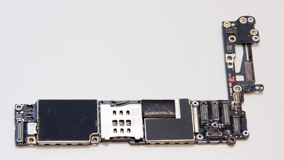 Hovedkortet sett forfra. SIM-kortholderen sees i midten. Apples A8-prosessor sitter til høyre for denne. De fleste komponentene er beskyttet av metalldeksler som er loddet fast i kretskortet.