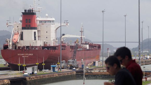 To personer ser et skip passere gjennom Miraflores-slusene i Panamakanalen.