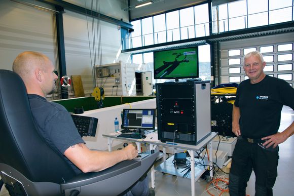 Tester: Ronny Liøkel kan sitte godt i en stol inne i fabrikkhallen for å teste en ROV i bassenget ved siden av. På skjermen ser han hvordan verktøyet for å reparere merder fungerer.