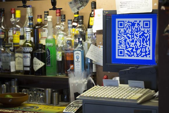 9. oktober i år installerte en pub i London, Pembury Tavern, et kasseapparat som lar kundene betale med bitcoin. QR-koden på kasseapparatets skjerm leses av en app på kundens mobiltelefon. Deretter overføres beløpet i bitcoin fra kunde til pub. <i>Bilde: Bloomberg via Getty Images/Getty Images/All Over Press</i>