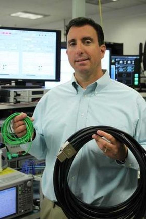 Mario Paniccia  med en 1,6 terabit per sekund MXC-kabel (grønn) og en kobberbasert 128 gigabit per sekund PCI Express-kabel. <i>Bilde: Intel</i>