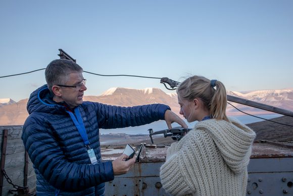 Første droneinstruksjon: Leder fro UAS Norway Anders Martinsen gir Penelope Lea i Miljøagentene en første instruksjon i droneflygning utenfor gruvemuseet i gruve 3 i Longyearbyen <i>Foto:  Odd R. Valmot</i>