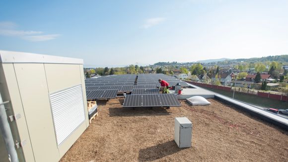 Installeringen av totalt 126 solcellepaneler er i gang på taket av Lyngården. Hvert panel yter 310 watt, noe som vil gi en produksjon på 39 kW ved optimale forhold. Strømmen som produseres av solcellene går rett ned til elbilladerne i kjelleren. <i>Foto:  Håvard Zeiner</i>