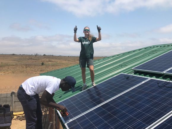 En av de 50 frivillige som har reist ut på oppdrag for Ingeniører uten grenser er Oda Grifftun. Her hjelper hun til å legge solpaneler på et tak i i Zimbabwe. <i>Foto:  Ingeniører uten grenser</i>