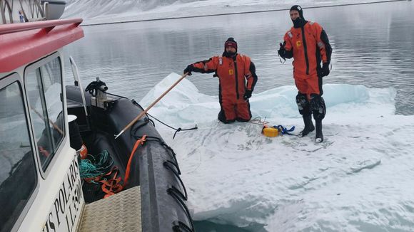 Aleksey Marchenko fra Universitetssenteret på Svalbard (UNIS) og Trygve Kvåle Løken (t.h.) gjør isfjellet klart til taueeksperiment. <i>Foto:  Audun Tholfsen/UNIS</i>