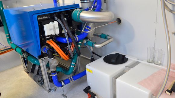 Brenselcellene som produserer strøm ligger inne i denne blå boksen, mens plastanken nederst til høyre samler opp vann som blir det eneste avfallsstoffet fra prosessen. <i>Foto: Thomas Førde</i>