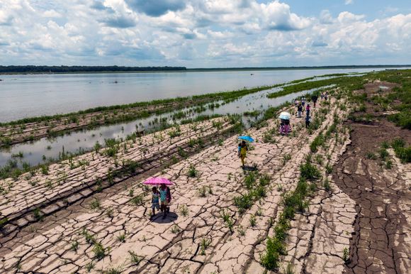 Folk går langs en del av Amazon-elven som viser tegn på dørke i Santa Sofia utenfor Leticia i Colombia i oktober. <i>Foto:  </i>