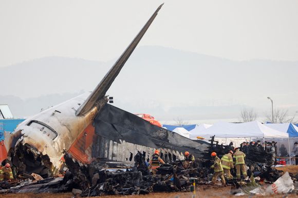 Folk arbeider på stedet der et fly kjørte av rullebanen og krasjet på Muan internasjonale lufthavn i Muan i Sør-Korea. <i>Foto:  Kim Soo-hyeon/Reuters/NTB</i>