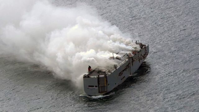 Brennende lasteskip blir tauet mot trygg fortøyning