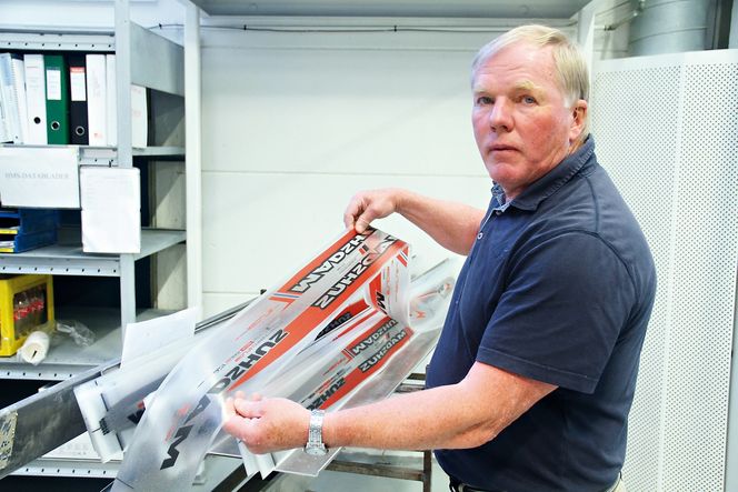 Senior adviser Gunnar Bjertnæs viser folien av plexiglass som danner overflaten med dekor på den ferdige skien. RFID-brikken er festet til folien.