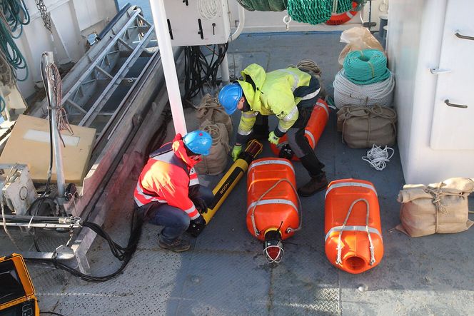 Klargjøring av node, som skal legges inn i flytekragen. Hampetau og striesekk med sand festets i for å gi ballast. Når sonden skal hentes opp, frigjøres den fra tauet. Tau og sekk går i oppløsning, mens sanden er godkjent for stedet.