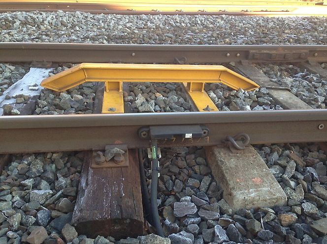 Akselteller med oppkjørsbjelke (gul). Bjelken forhindrer at vedlikeholdsmaskiner løftes opp for å unngå å ødelegge akseltelleren.