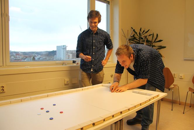 Magnetspillet kommer ikke med et brett, men kan benyttes på en rekke flater. Her spilles en form for curling på stuebordet.