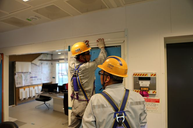 I kontrollrommet monterer to Samsung-arbeidere lister.