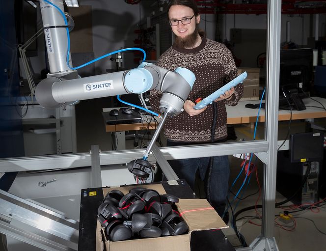 Trondheim 03.12.2013 : forskerne er Sigurd Albreksten,og Torstein Myhre. Fotografering av et par roboter ned i NTNU/SINTEF Raufoss sin labb på SINTEF Teknologi og samfunn? - Det ene er en robot som plukker stolhjul. Jeg har en liten video av selve plukkingen- så bildet må bli med forsker/pc i forgrunn og robot i bakgrunnen. Forsker med robot og glidende stativ med plater som skal lakkeres. Foto Thor Nielsen