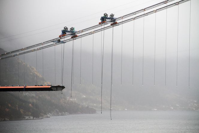 HEIS: Kranene som brukes til å heise brukassene opp ruller på hovedkablene, og er stabilisert med traversstag. Det er ikke tvunnet vaier som benyttes til å løfte kassene, men spennstål.